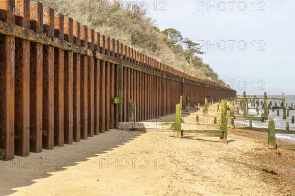Steel sheet piling sea wall old broken wooden groynes coastal defences, Bawdsey, Suffolk, England, UK