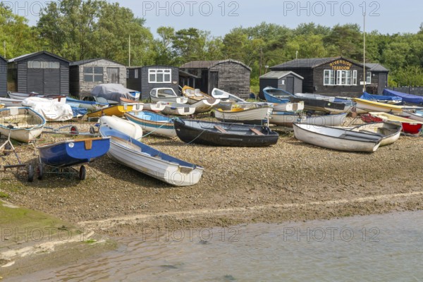 Dinghies on beach with black fishing sheds and Riverside Tearoom cafe, Orford, Suffolk, England, UK