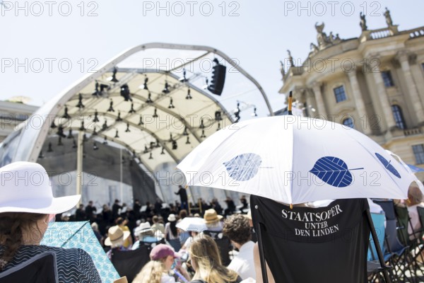 Audience with sun protection at the Staatsoper für alle, a free open-air concert with conductor Christian Thielemann and the Staatskapelle Berlin on Berlin's Bebelplatz, Berlin, 22 June 2025