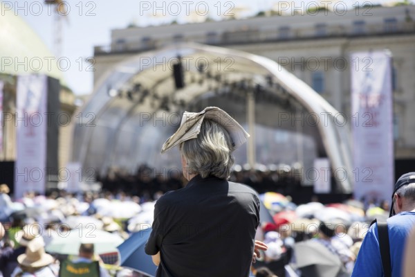 A visitor protects himself from the sun with a newspaper on his head at the Staatsoper für alle, a free open-air concert with conductor Christian Thielemann and the Staatskapelle Berlin on Berlin's Bebelplatz, Berlin, 22 June 2025
