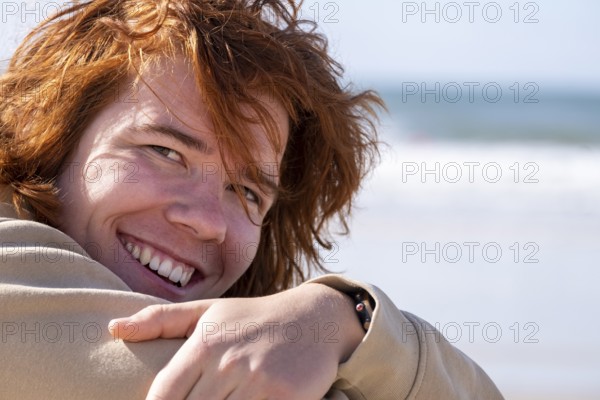 Young man with red hair, sitting on the beach, Jeffreys Bay near Port Elizabeth, Garden Route, Eastern Cape, South Africa