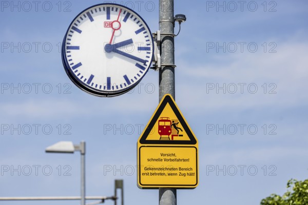 Platform with signs, station clock and warning sign Caution, fast passing. Karlsruhe, Baden-Württemberg, Germany