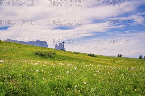 Wide meadow with cross and cable car in the background under a blue sky, Alpe di Siusi, Dolomites, South Tyrol, Italy