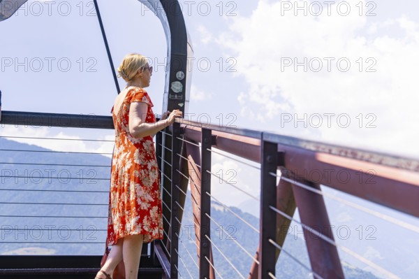 A woman stands on a viewing platform and looks at the surrounding mountains, Botanical Garden, The Gardens of Trauttmansdorff Castle, Merano, South Tyrol, Italy
