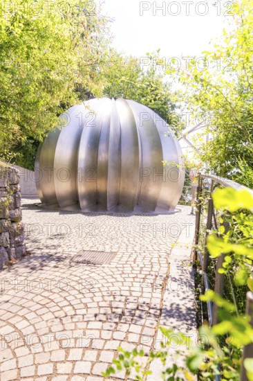 Modern metal sculpture in a sunny park with green foliage in the background, Botanical Garden, The Gardens of Trauttmansdorff Castle, Merano, South Tyrol, Italy