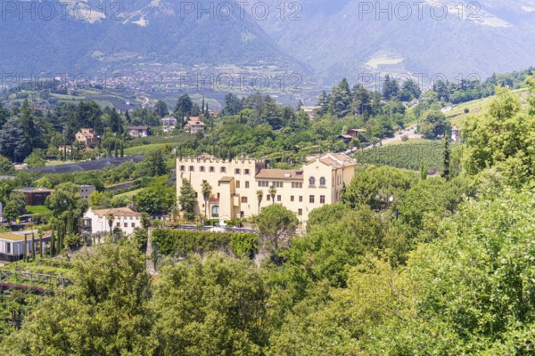Castle surrounded by green nature and mountain landscape with small village nearby, botanical garden, The Gardens of Trauttmansdorff Castle, Merano, South Tyrol, Italy