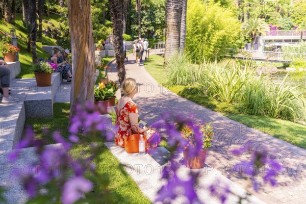 People relaxing in a sunny park with flowers and green grass, Botanical Garden, The Gardens of Trauttmansdorff Castle, Merano, South Tyrol, Italy