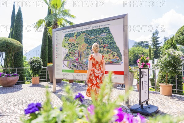 Woman in front of an information board in a sunny garden area, Botanical Garden, The Gardens of Trauttmansdorff Castle, Merano, South Tyrol, Italy