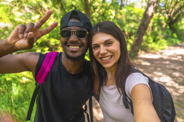 Smiling hikers capturing a selfie while enjoying their adventure on a bright, sunny day in the lush forest, surrounded by nature