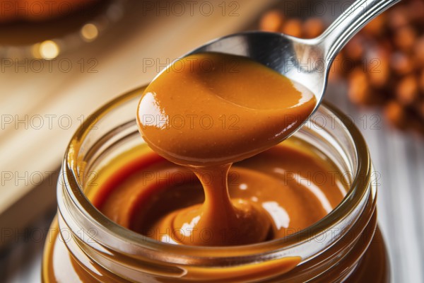 Close-up of silver spoon scooping rich pumpkin butter from glass jar. Warm autumn kitchen scene emphasizing texture and cozy atmosphere. Generative ai, AI generated