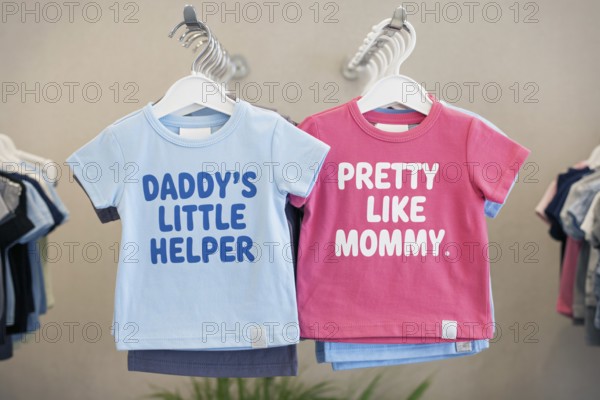 Pink and blue children's shirts with stereotypical text, highlighting early gender norms and societal expectations. Generative AI, AI generated