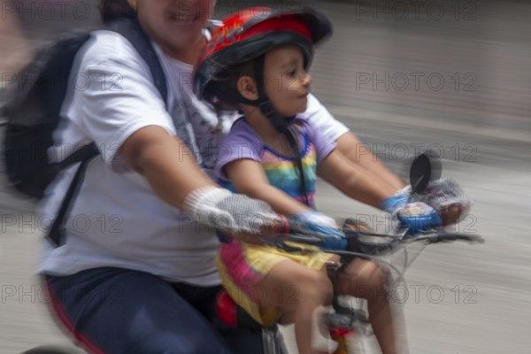 Woman and kid riding a bicycle, Photo with motion blur, City of Quito, Pichincha province, Ecuador, South America