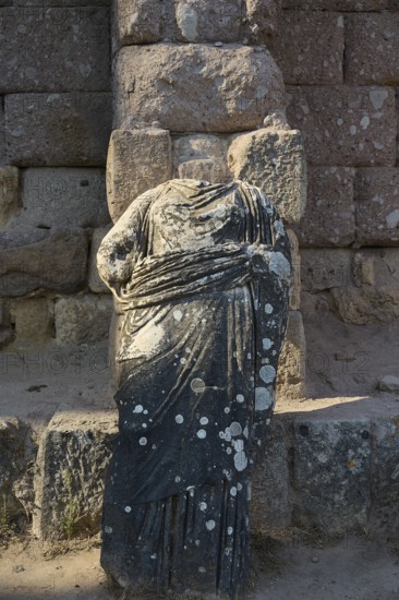 Damaged stone statue in antique garment in front of an old stone wall, antique statue of gods, Asklipion, Asklepieion, healing temple, temple, Hippocrates, Kos, Dodecanese, Greek Islands, Greece
