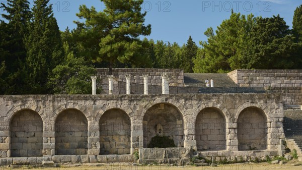 Wide angle view of ancient ruins and stone arches with dense forest in the background, retaining wall with arcades, Asklipion, Asklepieion, healing temple, temple, Hippocrates, Kos, Dodecanese, Greek Islands, Greece