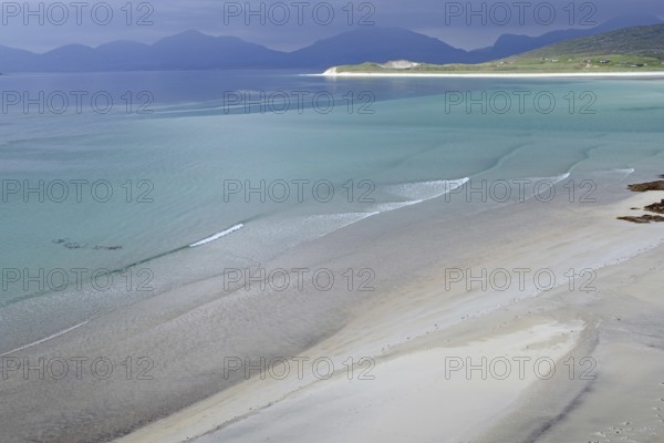 Wide, empty sandy beach with gentle waves, surrounded by mountains and a calm sea, Seilebost Beach, Isle of Harris, Hebrides, Scotland, United Kingdom