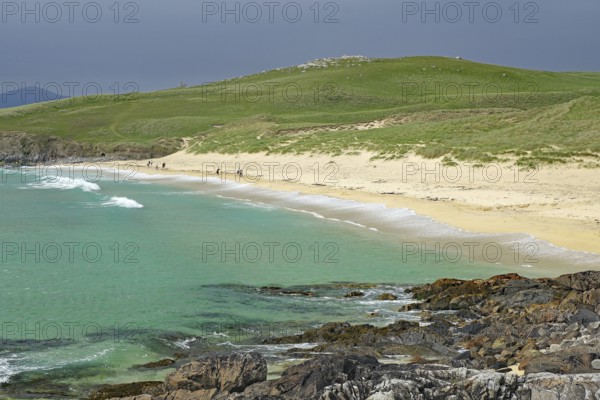 Picturesque coastal landscape with green hill, sandy beach and turquoise sea under a cloudy sky, Isle of Lewis, Hebrides, Scotland, Great Britain