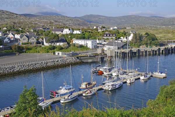 Small harbour with sailing boats in front of a coastal town in a hilly landscape, Tarbert, Isle of Lewis, Hebrides, Scotland, United Kingdom