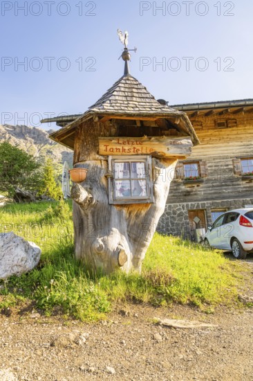 Whimsical wooden petrol station in a rural setting with car and meadow, Alpe di Siusi, Dolomites, South Tyrol, Italy