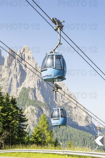 Blue cable car gondolas in front of a rocky mountain backdrop in fine weather, Alpe di Siusi, Dolomites, South Tyrol, Italy