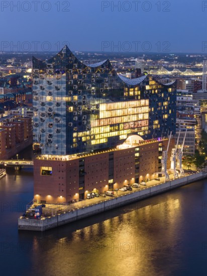 Aerial view of the Elbphilharmonie at blue hour with illuminated windows and view over the Speicherstadt and Hafencity, Hamburg, Germany