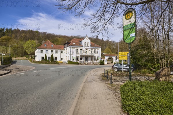 Hotel and restaurant Wittekindsquelle, building, bus stop church, pavement, concrete paving stones, asphalt road, trees, forest, blue sky, cirrostratus clouds, intersection Volmerdingsener Straße with Bergkirchener Straße, Bad Oeynhausen, Mühlenkreis Minden-Lübbecke, North Rhine-Westphalia, Germany