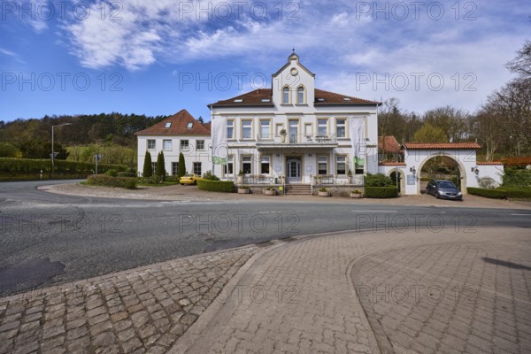 Hotel and restaurant Wittekindsquelle, building, pavement, concrete paving stones, asphalt road, trees, forest, blue sky, cirrostratus clouds, intersection of Volmerdingsener Straße and Bergkirchener Straße, Bad Oeynhausen, Mühlenkreis Minden-Lübbecke, North Rhine-Westphalia, Germany