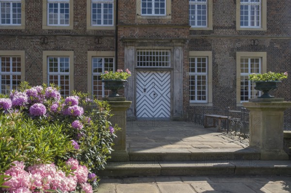An elegant entrance to a historic brick building with flowering plants, Haus Welbergen, Ochtrup, Welbergen, Münsterland, North Rhine-Westphalia, Germany