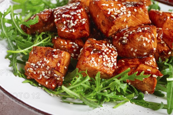 Fried salmon slices, teriyaki with sesame seeds, with arugula salad, top view