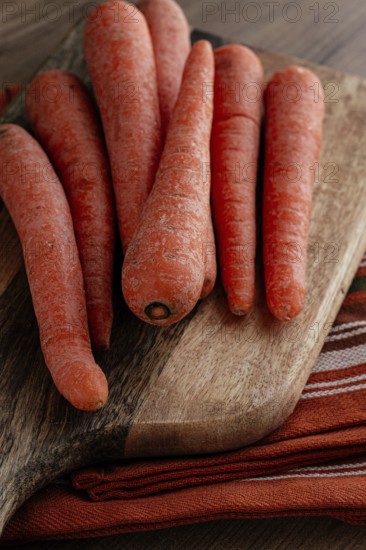 Fresh carrots on a chopping board, wooden table, raw carrots, no people