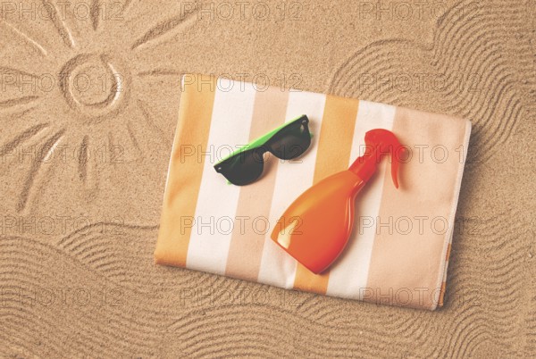 Drawing on the sand, sun and waves, sunglasses, with an orange bottle, beach towel, sun spray, on the sand, top view, no people