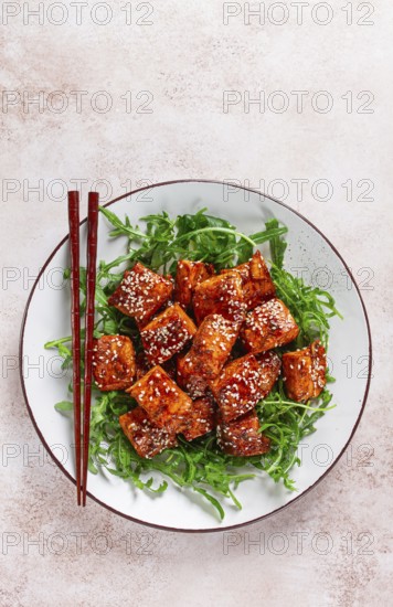 Fried salmon slices, teriyaki with sesame seeds, with arugula salad, top view