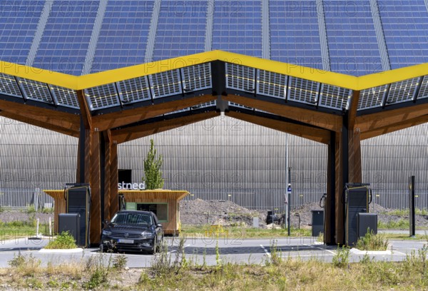 Electric charging station on the site of the former Lohberg colliery in Dinslaken, operated by Fastned, uses electricity from wind power and solar energy, fast-charging columns, with its own solar roof, in the background the 11, 500 square metre solar roof on the colliery's former coal mixing hall, North Rhine-Westphalia, Germany