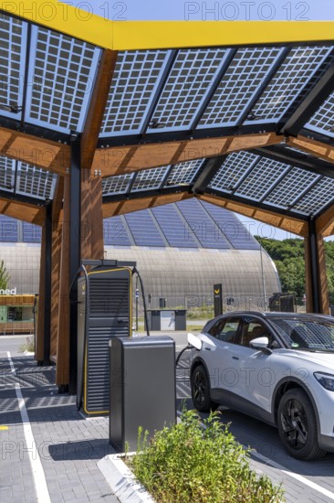 Electric charging station on the site of the former Lohberg colliery in Dinslaken, operated by Fastned, uses electricity from wind power and solar energy, fast-charging columns, with its own solar roof, in the background the 11, 500 square metre solar roof on the colliery's former coal mixing hall, North Rhine-Westphalia, Germany