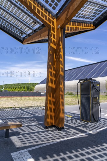 Electric charging station on the site of the former Lohberg colliery in Dinslaken, operated by Fastned, uses electricity from wind power and solar energy, fast-charging columns, with its own solar roof, in the background the 11, 500 square metre solar roof on the colliery's former coal mixing hall, wind farm on the Lohberg slagheap, North Rhine-Westphalia, Germany