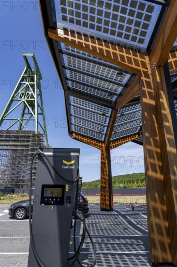 Electric charging station on the site of the former Lohberg colliery in Dinslaken, operated by Fastned, uses electricity from wind power and solar energy, fast-charging columns, with its own solar roof, wind farm on the Lohberg spoil tip, Lohberg colliery headframe, North Rhine-Westphalia, Germany