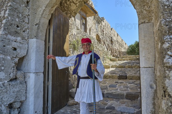 Man in traditional traditional costume kindly standing in front of historic archway, Antimacheia, Medieval Fortress, St John's Fortress, Antimachia, Kos, Dodecanese, Greek Islands, Greece