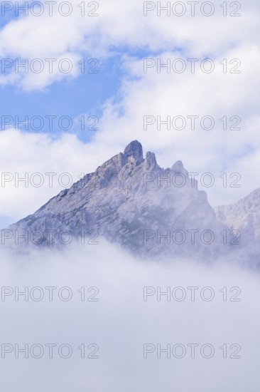 An isolated mountain peak rises through fog into the clear sky, Dolomites, South Tyrol, Dolomites, Italy