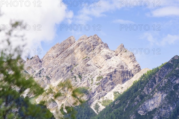 Mountain landscape with rocky peak and blue sky, surrounded by green nature, Alpe di Siusi, South Tyrol, Dolomites, Italy