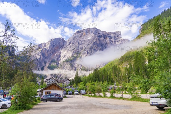 Car park in front of an impressive mountain landscape with cars and buildings in the countryside, Pragser Wildsee, South Tyrol, Dolomites, Italy
