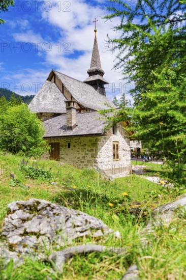 Stone church with characteristic tower in a green, sunlit landscape, Lake Braies, South Tyrol, Dolomites, Italy
