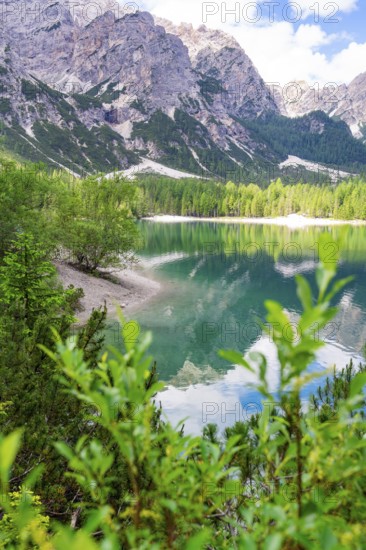 A tranquil mountain lake, surrounded by trees and mountains, reflects the sky and the surrounding landscape, Lake Braies, South Tyrol, Dolomites, Italy