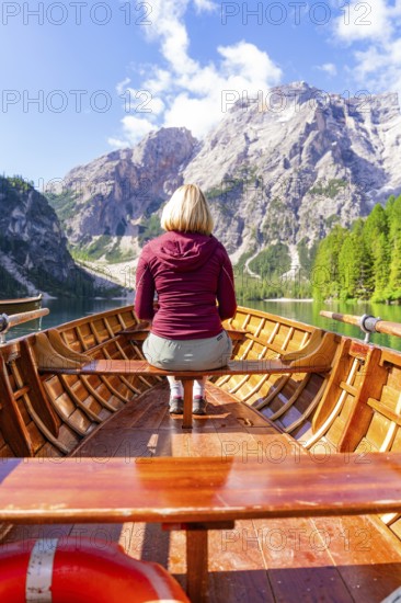 Back view of a woman in a boat on a mountain lake in sunny surroundings, Pragser Wildsee, South Tyrol, Dolomites, Italy