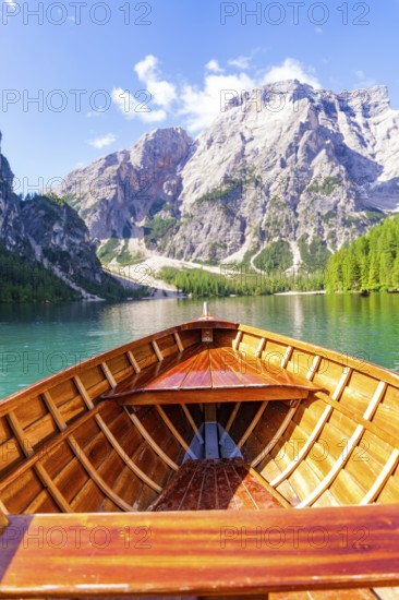 View from the boat onto a calm lake with surrounding mountain panorama under a clear sky, Lake Braies, South Tyrol, Dolomites, Italy
