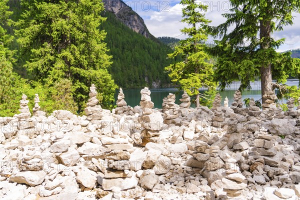 Cairn in the forest with water in the background, natural environment, Lake Braies, South Tyrol, Dolomites, Italy