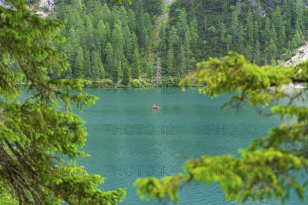 A single boat on a calm turquoise-blue lake, framed by green trees, Pragser Wildsee, South Tyrol, Dolomites, Italy