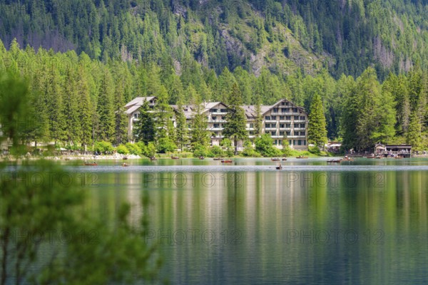 A hotel on the lake shore with surrounding trees and mountains, quiet atmosphere, Lake Braies, South Tyrol, Dolomites, Italy