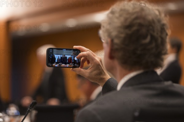 A person takes a photo with their mobile phone in front of the meeting of Federal Chancellor Friedrich Merz with the heads of government of the federal states in the International Conference Hall of the Federal Chancellery, Berlin, 18 June 2025