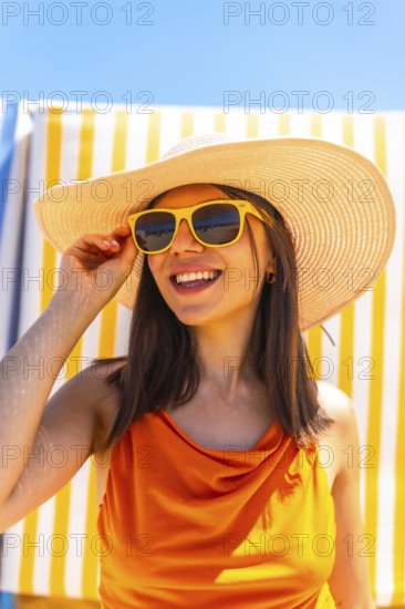 Carefree tourist with yellow sunglasses and straw hat enjoying summer vacation at beach resort
