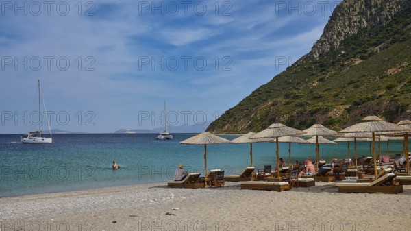 Kamari beach, summer beach scenery with deckchairs and parasols, two sailing boats in the calm blue sea, Kefalos, Kos, Dodecanese, Greek Islands, Greece