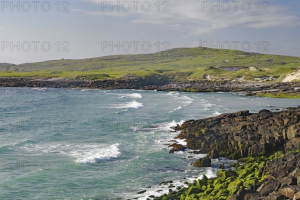 Rocky coastline with strong waves and green grassland under a cloudy sky, wild, Isle of Barra, Hebrides, Scotland, United Kingdom
